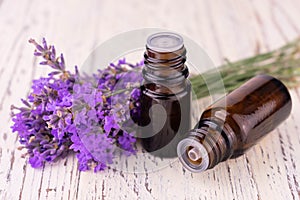 Two bottles with fragrant lavender oil and delicate lavender flowers on a white background.