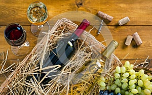 Two bottles, glasses of wine, bunches of grapes on wooden table