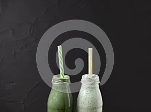 Two bottles of green smoothie made from spirulina and yogurt on a black background