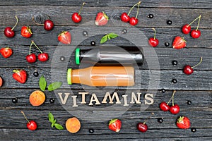 Two bottles of juice, the inscription Vitamins and fruits. Wooden background.