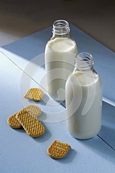 Two bottles of milk and cookies, breakfast on a blue background