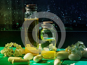 Two bottles of oil, next to the medicine, on a dark background and drops of water. The concept of alternative medicine