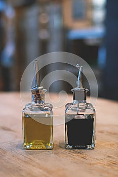 Two bottles of olive oil and of balsamico on the rustic table.
