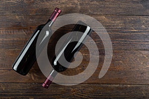 Two bottles of red wine on a wooden background