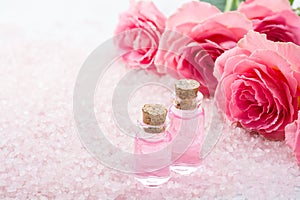 Two bottles with rose oil, spa salt crystals and pink roses