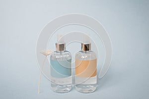 Two bottles of serum of perfume are on a blue background