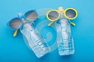 Two bottles of water on a blue background are similar to people sunbathing on the beach, bottled glasses, concept summer