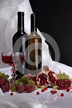 Two bottles of wine on a background of pomegranate and grapes