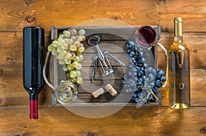 Two bottles of wine and grapes in  box on  wooden background