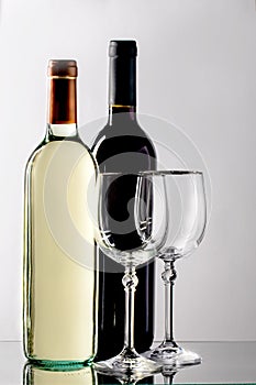 Two bottles of wine with tap and white wine and two glasses on a thin stem