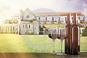 Two bottles of wine and two glasses against the background of an ancient monastery. With space for text