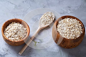 Two bowls with oat flakes and wooden spoon isolated on white background, close-up, top view, selective focus.