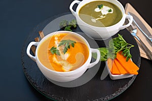 Two bowls of pumpkin and broccoli soup with cream