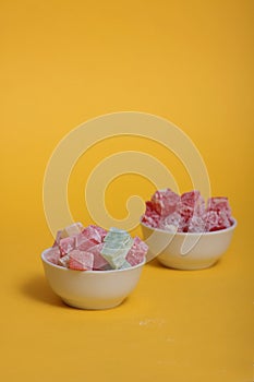 Two bowls of rahat lakoum isolated on yellow background. Turkish sweet concept