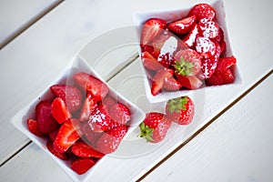 Two bowls of strawberries with sugar and mint. Top down view