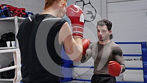 Two boxer man training together on boxing ring in fight club. Fighter man training fight in boxing gloves while sparring