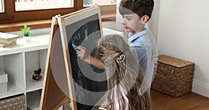 Two boy and girl drawing in chalk on play blackboard