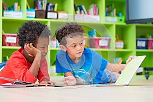 Two boy kid lay down on floor and reading tale book in preschoo