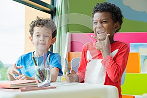 Two boy kid sit on table and coloring in book in preschool libr