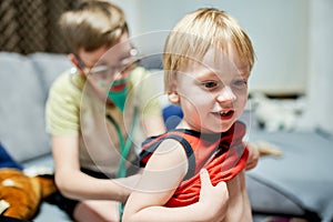 Two boys 11 years old and 3 years old playing doctor and patient at home.