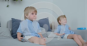 Two boys, 4 and 2 years old, are watching TV sitting on the couch. An exciting TV show. View cartoons