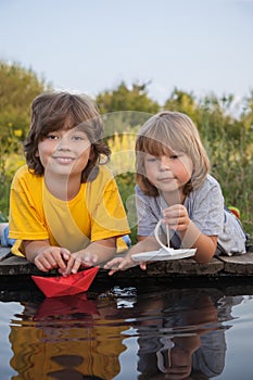 Two boys allowed paper boats from the pier of river