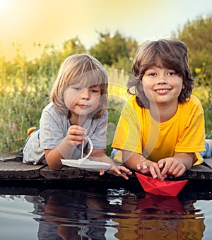 Two boys allowed paper boats from the pier of river