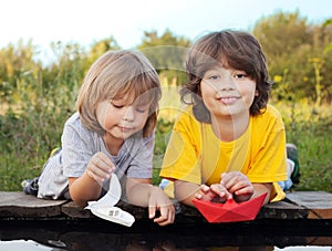 Two boys allowed paper boats from the pier of river