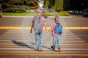 Two boys with backpack walking, holding on warm day on the road photo