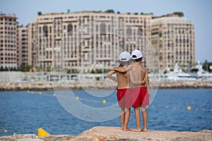 Two boys on the beach, having fun on a rock pier