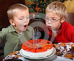 Two boys is blowing candles