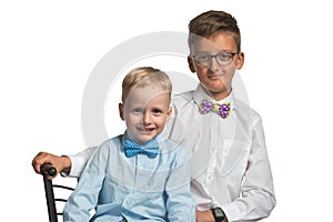 Two boys brothers sitting on a chair in shirt and butterfly isolated on white background