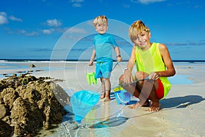 Two boys with butterfly net on the sand beach catching crabs