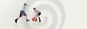 Two boys, children in classical retro clothes playing basketball over grey studio background. Banner, flyer. Concept of