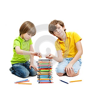 Two boys construct a tower from pencils