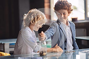 Two boys counting coins and putting them to the jar