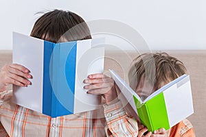 Two boys cover their faces with books. Mokap books. Imitation of careful reading concept of intelligence