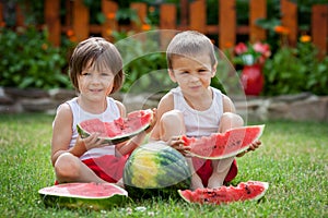 Two boys, eating watermelon in the garden, summertime