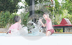 Two boys enjoy splashing water in the pool