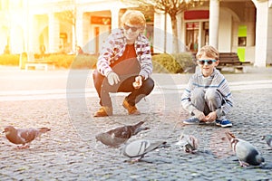 Dvaja chlapci kŕmia holubice na námestí
