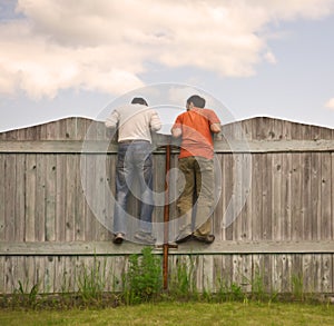 Two boys on the fence looking for smth