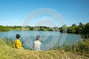 Two boys with fishing rods catch fish on the pond with a grandfather