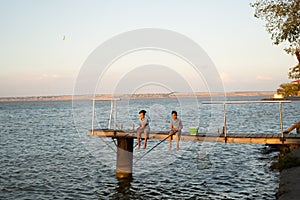 Two boys fishing at sunset on the lake, water background