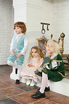 Two boys and girl in medieval costumes sit near