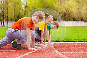 Two boys and girl stand on knee ready to run