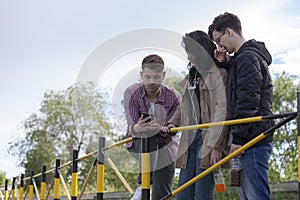 Two boys and a girl standing on the street and looking at the m