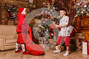 Two boys give each other gifts for Christmas. Santa costume