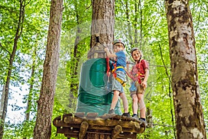 Two boys in a helmet, healthy teenager school boy enjoying activity in a climbing adventure park on a summer day