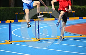 two boys jumping over hurdles