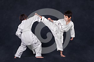 Two boys of the karateka in a white kimono battle